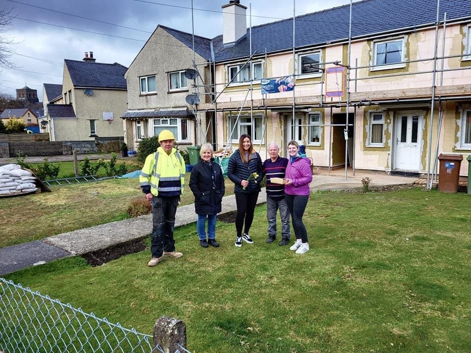 Staff from Claytons, Adra and local councillor Kim Jones giving an afternoon tea box to tenant outside his house i Llanberis